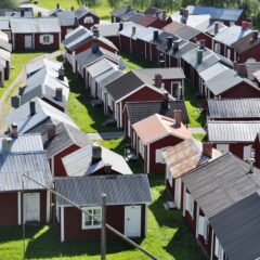 Vy över rödmålande trähus. De flesta hustak är i grå plåt.