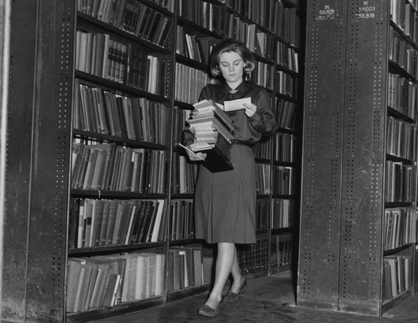 En bibliotekarie hämtar böcker i magasinen på LSE Library 1964, svartvit bild.