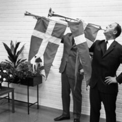 Två män blåser fanfar i varsin trumpet med svenska flaggan på.
