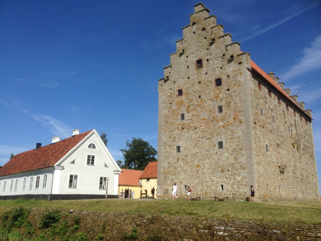 Borggården med längor och borg sedd från andra sidan vallgraven i soligt väder.
