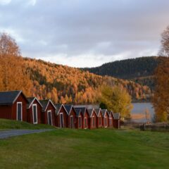 Röda småskaliga byggnader placerade i en sluttning. I bakgrunden syns träd i höstskrud.