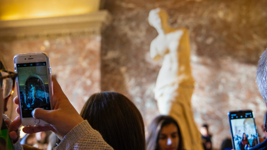 Personer fotograferar en Venus-staty med mobiltelefon.