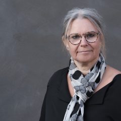 Porträttbild av Susanne Thedéen iklädd svart tröda och spräcklig sjal om halsen.