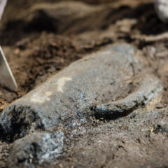 Närbild på arkeologiskt fynd, en slags kanna som ligger halvt dold i jord..