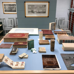 Arkivhandlingar, böcker och dokument av olika slag och form ligger utspridda på ett bord.