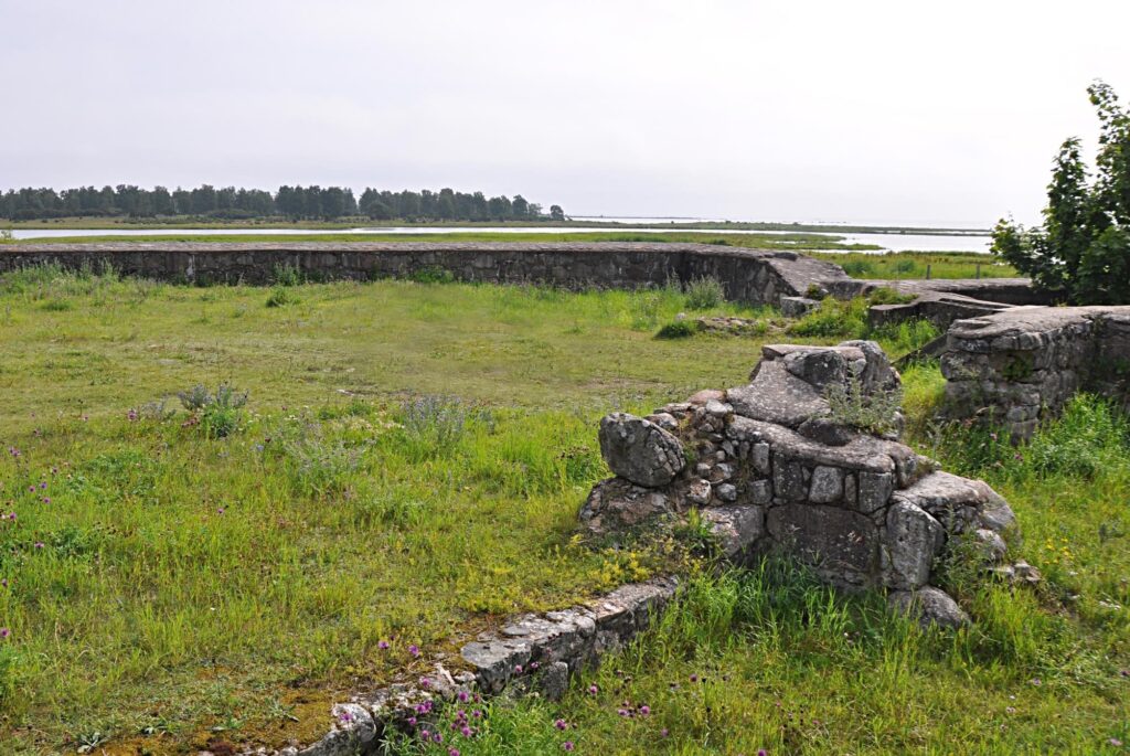 En låg stenmur i formation runt en grön gräsyta.