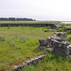 En låg stenmur i formation runt en grön gräsyta.