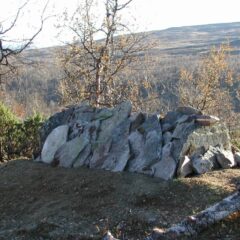 Bild på en grav övertäckt med stenar i ett fjälllandskap