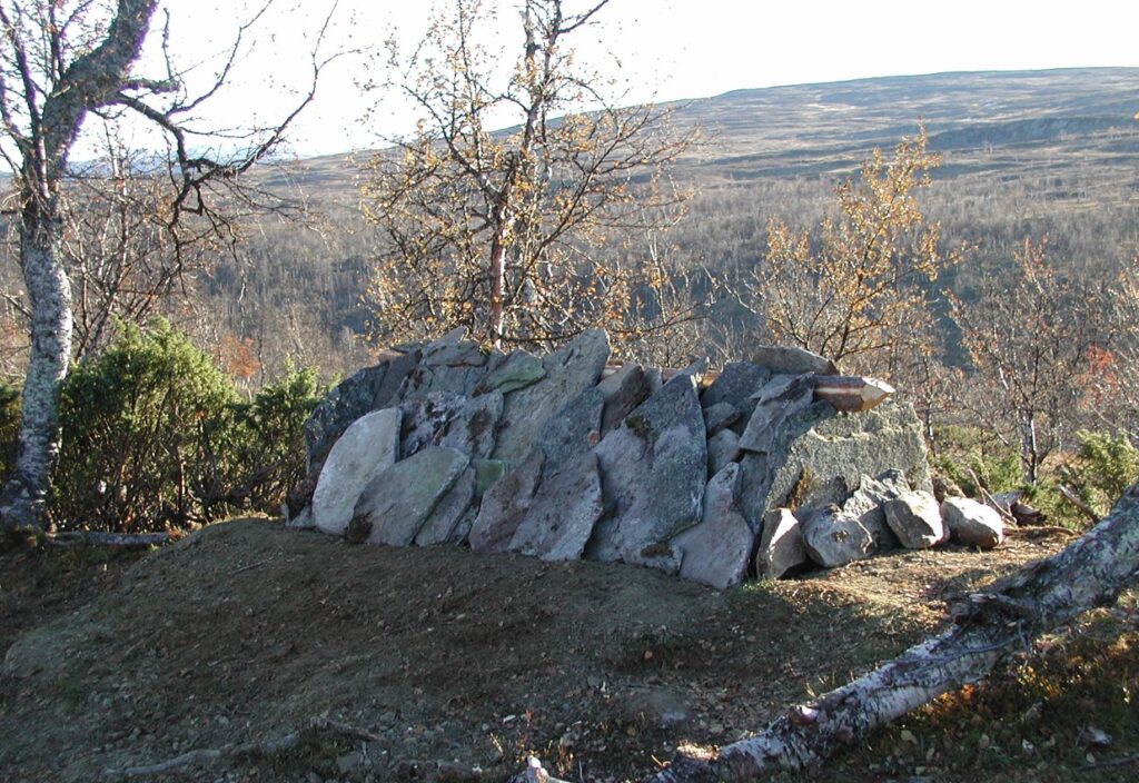 Bild på en grav övertäckt med stenar i ett fjälllandskap