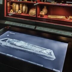 Monter med krukor och andra museiföremål. I förgrunden en röntgenbild på en digital skärm i ett bord.