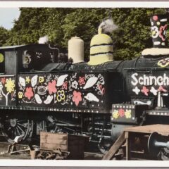 Ett svart ånglok är utsmyckat med massor att målande blommor.