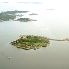 En lite blek bild från 90-talet med vy över havet . I mitten en ö med byggnader och runt om ön en mur.
