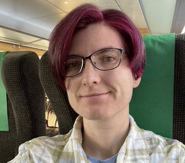 En kvinna i rött hår har tagit en selfie på ett tåg.