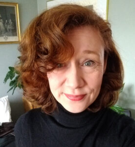 Mörkhårig kvinna med lockigt hår och lång lugg.