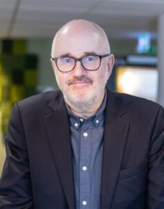 Medelålders man med rakat huvud, glasögon och mustasch.