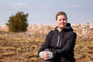 Kvinna sitter i ett höstlandskap med blå himmel.