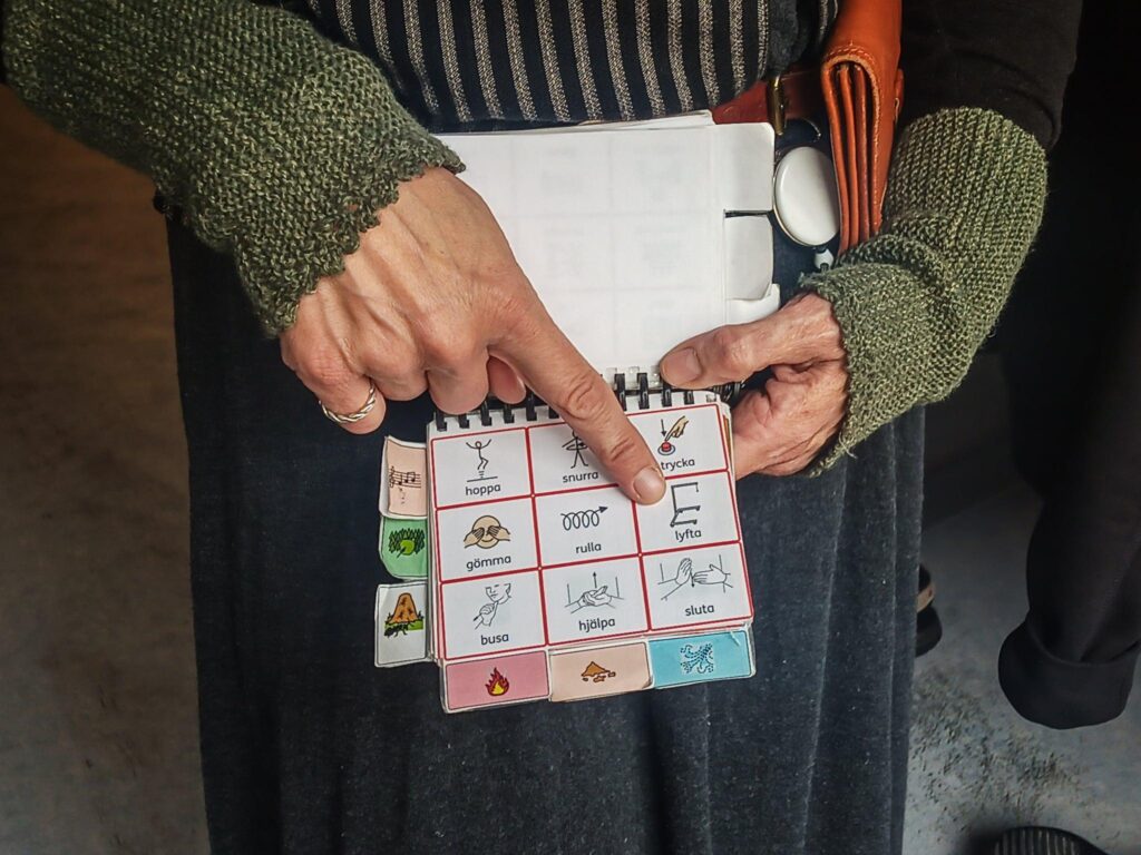 Hand pekar på ett block med olika kommunikativa symboler.