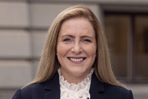 Närbild på kvinna med fasad i bakgrunden.