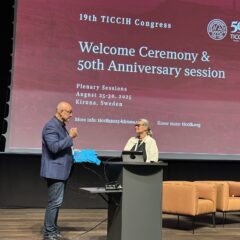 En man med blå kavaj står på en scen och talar i en mikrofon tillsammans med en en kvinna i vir kavaj.