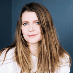 Porträtt på kvinna med långt brunt hår mot en blå bakgrund.