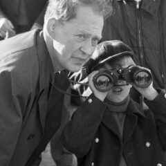 Pojke tittar i kikare, bredvid en vuxen man.