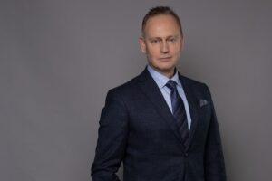 porträtt, man i mörk kostym, grå bakgrund.