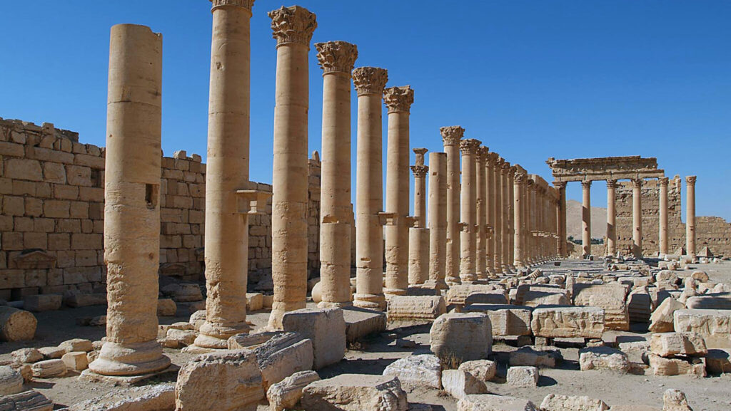 Vy över förstört tempel med tiotalet kolonner i rad med massor av nedrasade stenar bredvid.