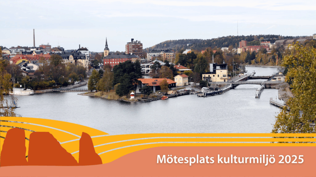 Vy över stad,, i förgrunden ett vattendrag.