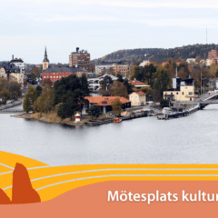 Vy över stad,, i förgrunden ett vattendrag.