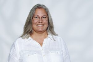 Porträtt på kvinna. Ljust halvlångt hår, vit skjorta, Inne, vit bakgrund.