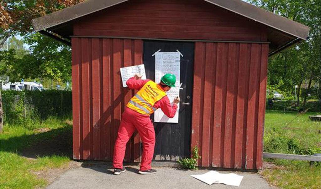 En man antecknar på ett blädderblockspapper som sitter fasttejpad på ett hus under en krisövning.