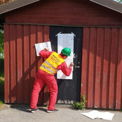 En man antecknar på ett blädderblockspapper som sitter fasttejpad på ett hus under en krisövning.