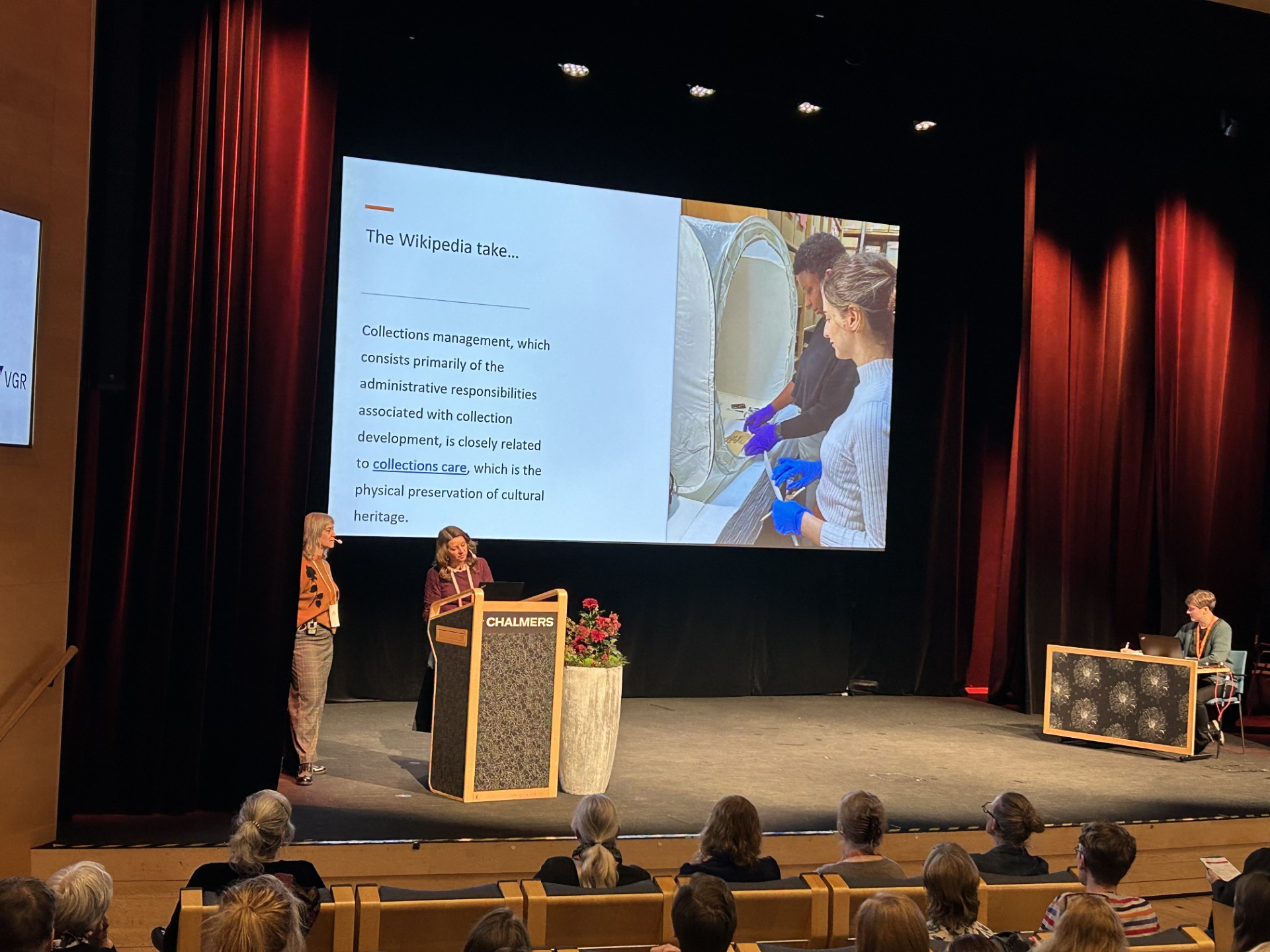 Två kvinnor håller ett föredrag vid ett podium på en scen.