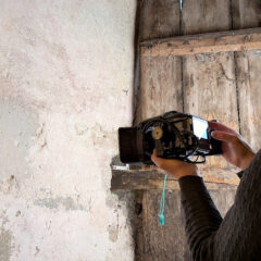 Person fotograferar en gammal trädörr och väggen intill på nära håll.