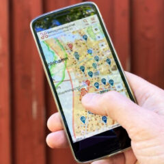 En hand håller en mobil som visar en karta.