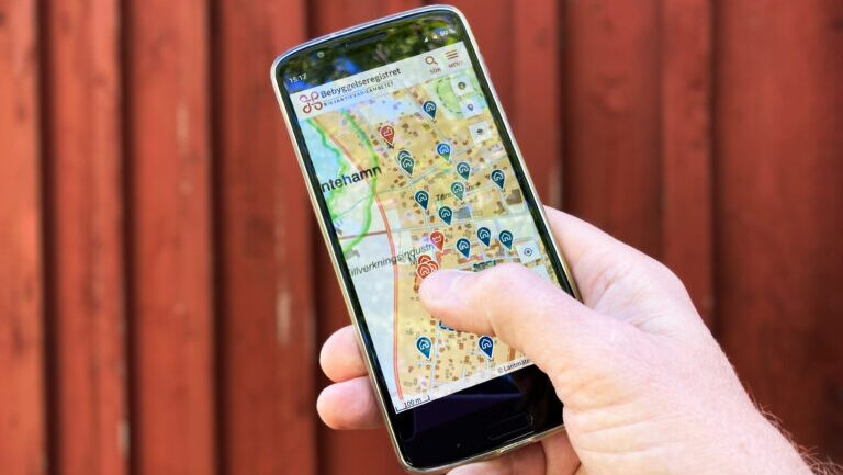En hand håller en mobil som visar en karta.
