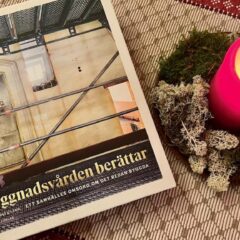 En bok ligger på ett bord med en julduk och ett tänt stearinljus.