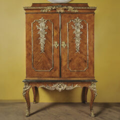 Ett träskåp med fyra ben och dekorationer på dörrarna.