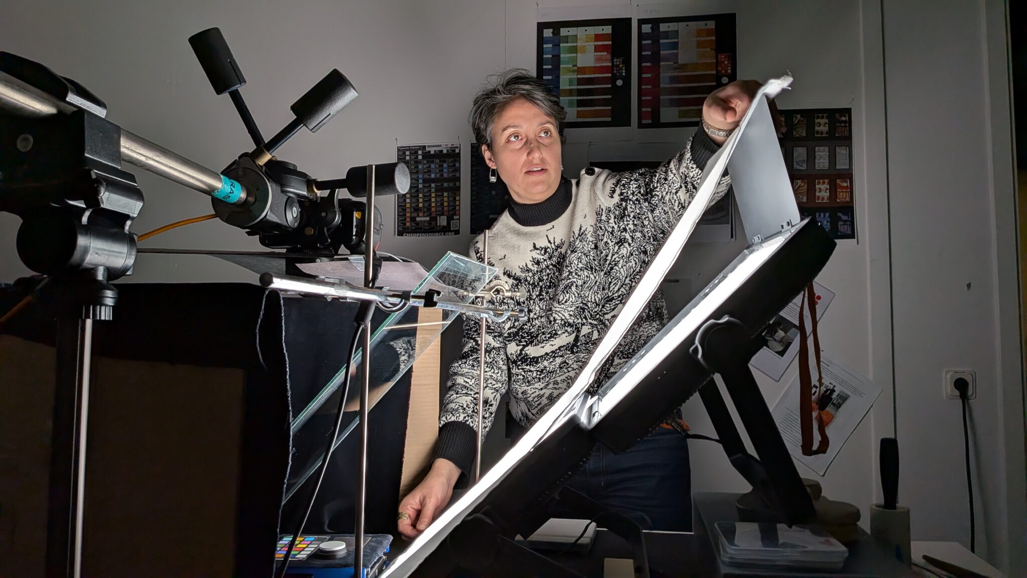 Kvinna står framför ett ljusbord och en ställning håller i en kamera på stativ.