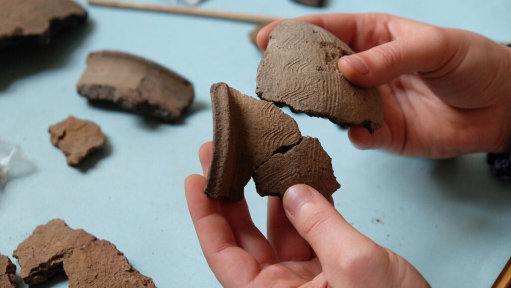 Arkeolog håller fynddelar i händerna.