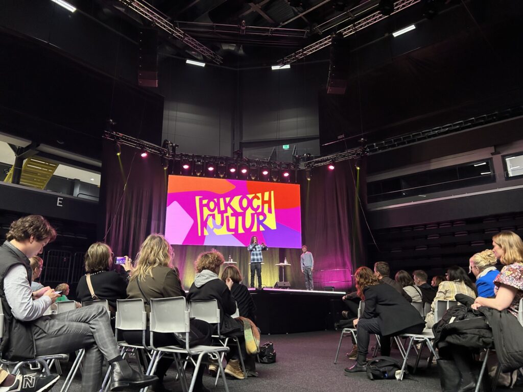 Människor sitter och lyssnar på föreläsaren på en scen