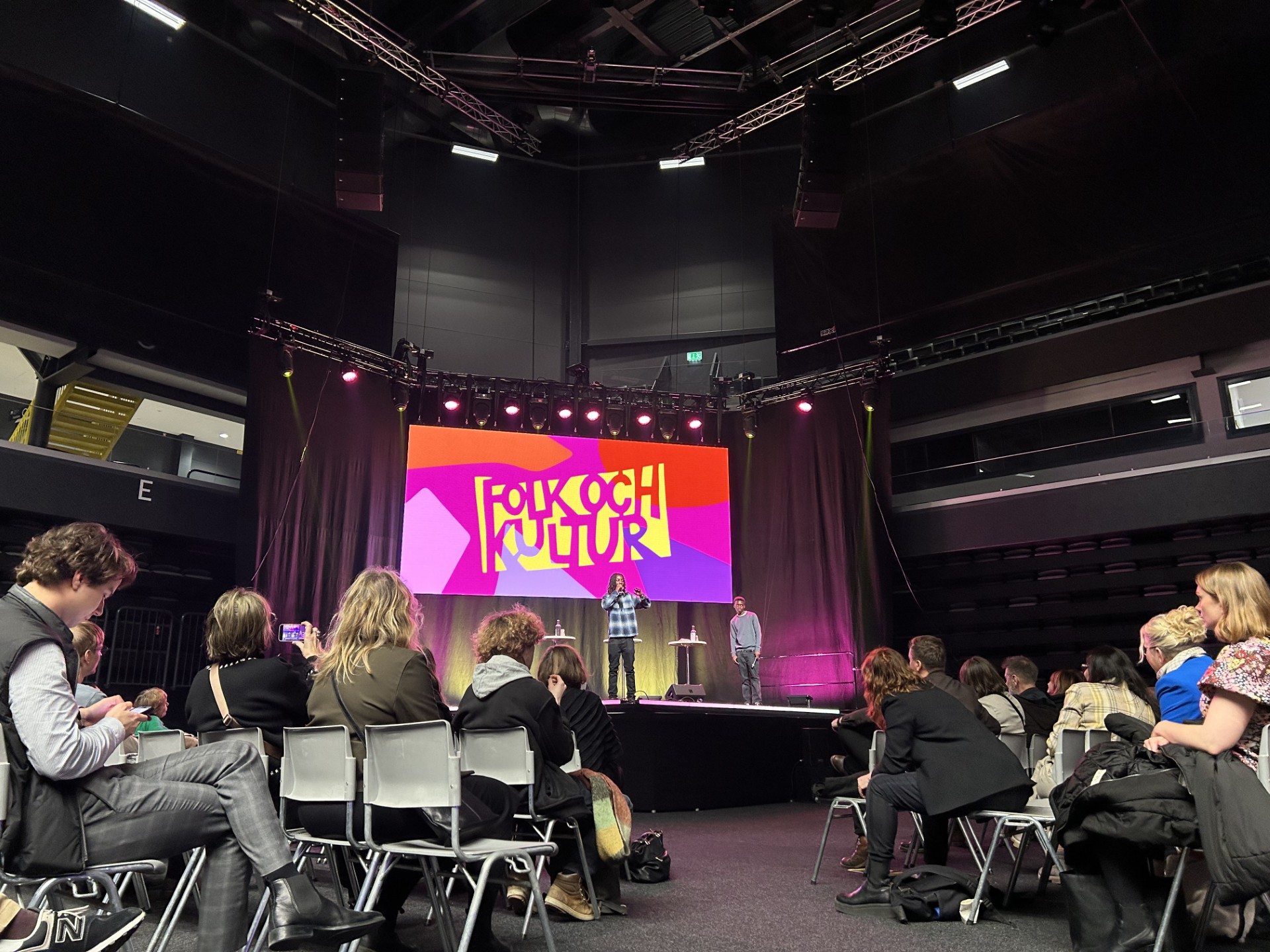 Människor sitter och lyssnar på föreläsaren på en scen