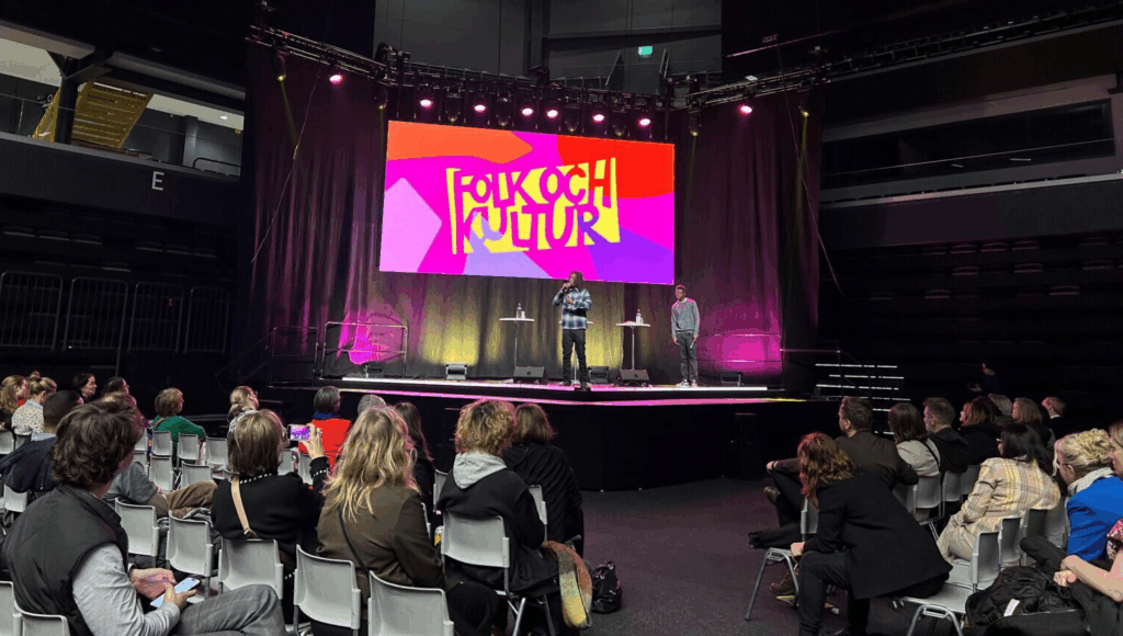 Människor sitter och lyssnar på föreläsaren på en scen