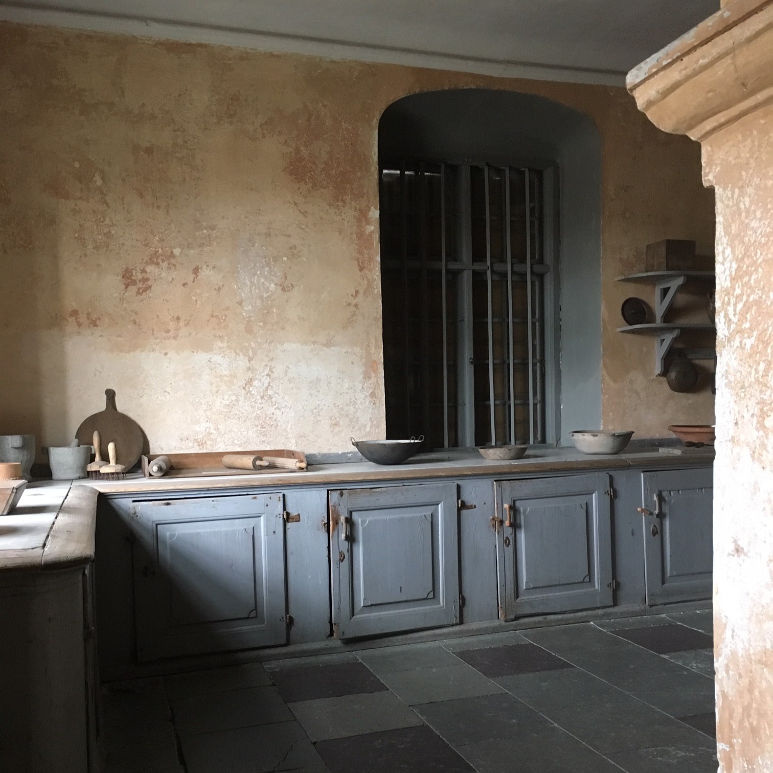 Ett äldre kök med gamla bemålade träbänkar och skåp.