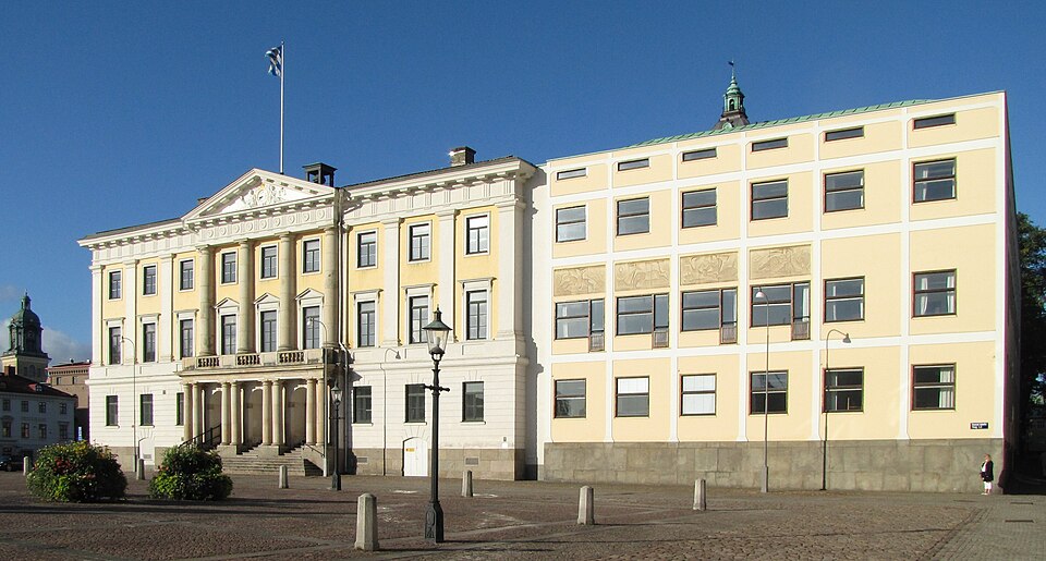 En stor gul byggnad i tre våningar med många fönster.