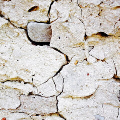 En sprucken putsfasad i vitt.