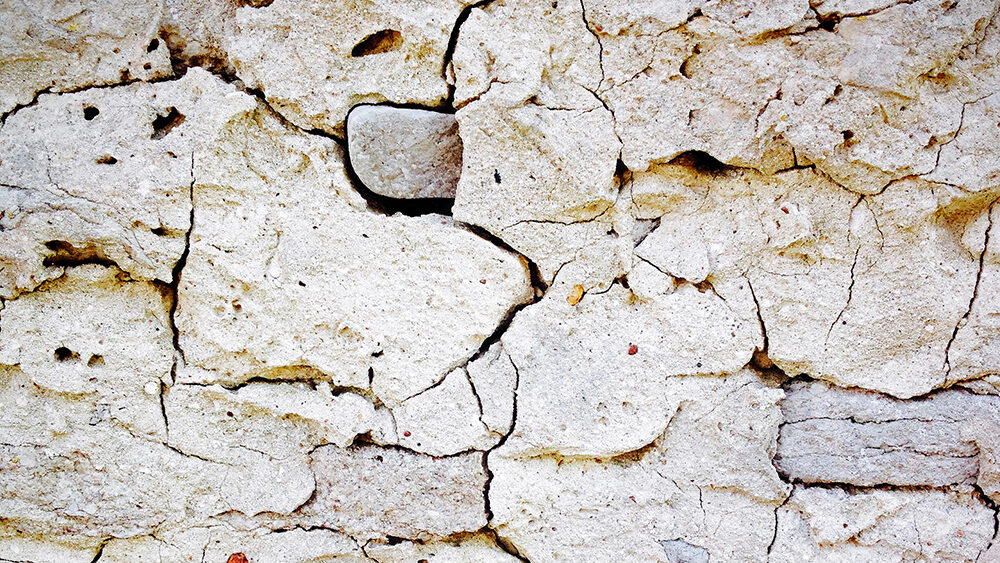 En sprucken putsfasad i vitt.