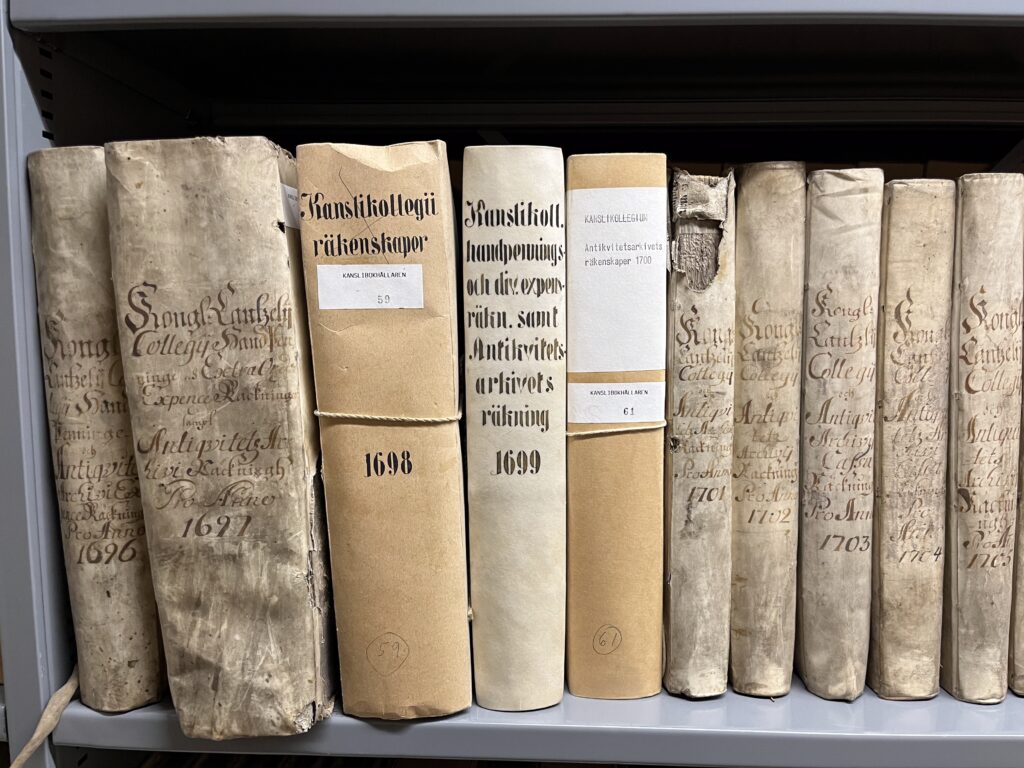 Flera äldre böcker står på rad, dessa har handskrivna titlar på bokryggen som beskriver innehållet.