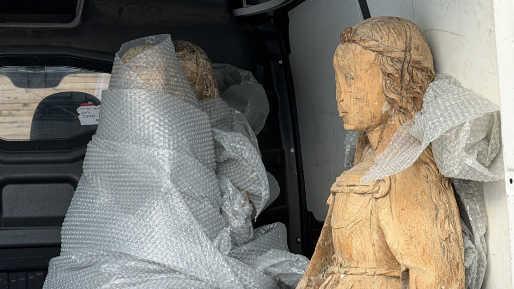 Inplastad staty och delvis inplastad staty under frakt i skåpbil.