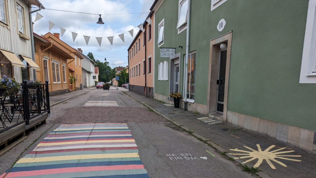 Stadsgata med hus i glada färger och målade trasmattor på asfalten.